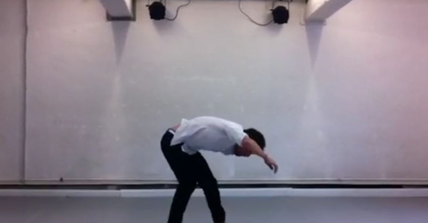 Paul Roberts tanzt: Er trägt ein weißes Hemd und dunkle Hose. Der Tänzer beugt sich nach vorne.